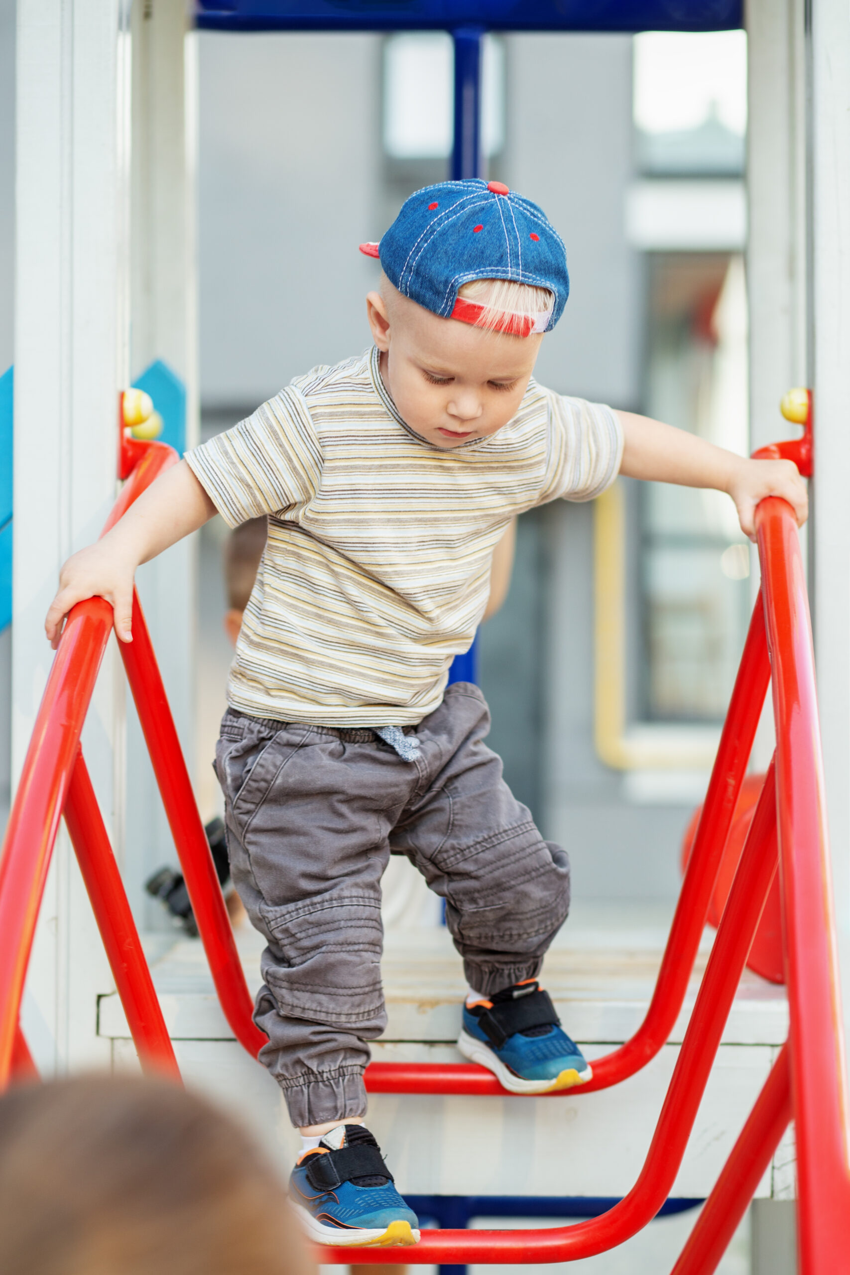 cute two year old boy plays on playground slide on summertime. kid play on kindergarten yard.